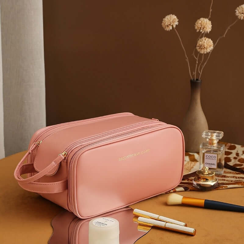Stylish pink double zipper cosmetic bag on a table with makeup brushes and a vase, perfect for household storage.