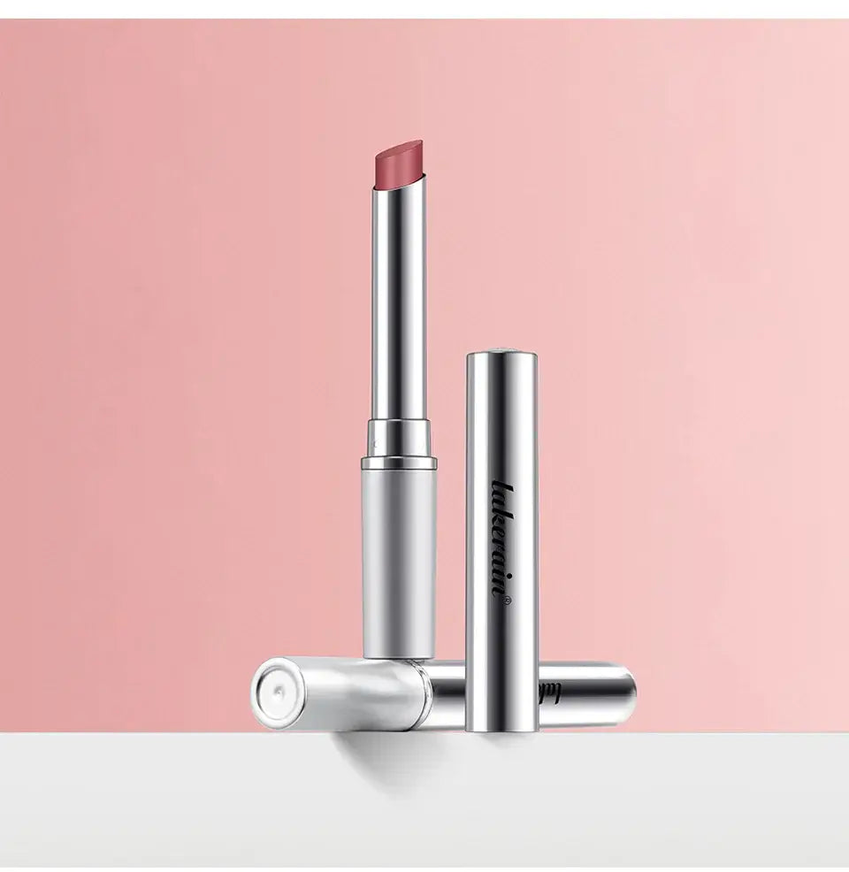 Long lasting black honey lipstick in sleek silver packaging on a pink background.