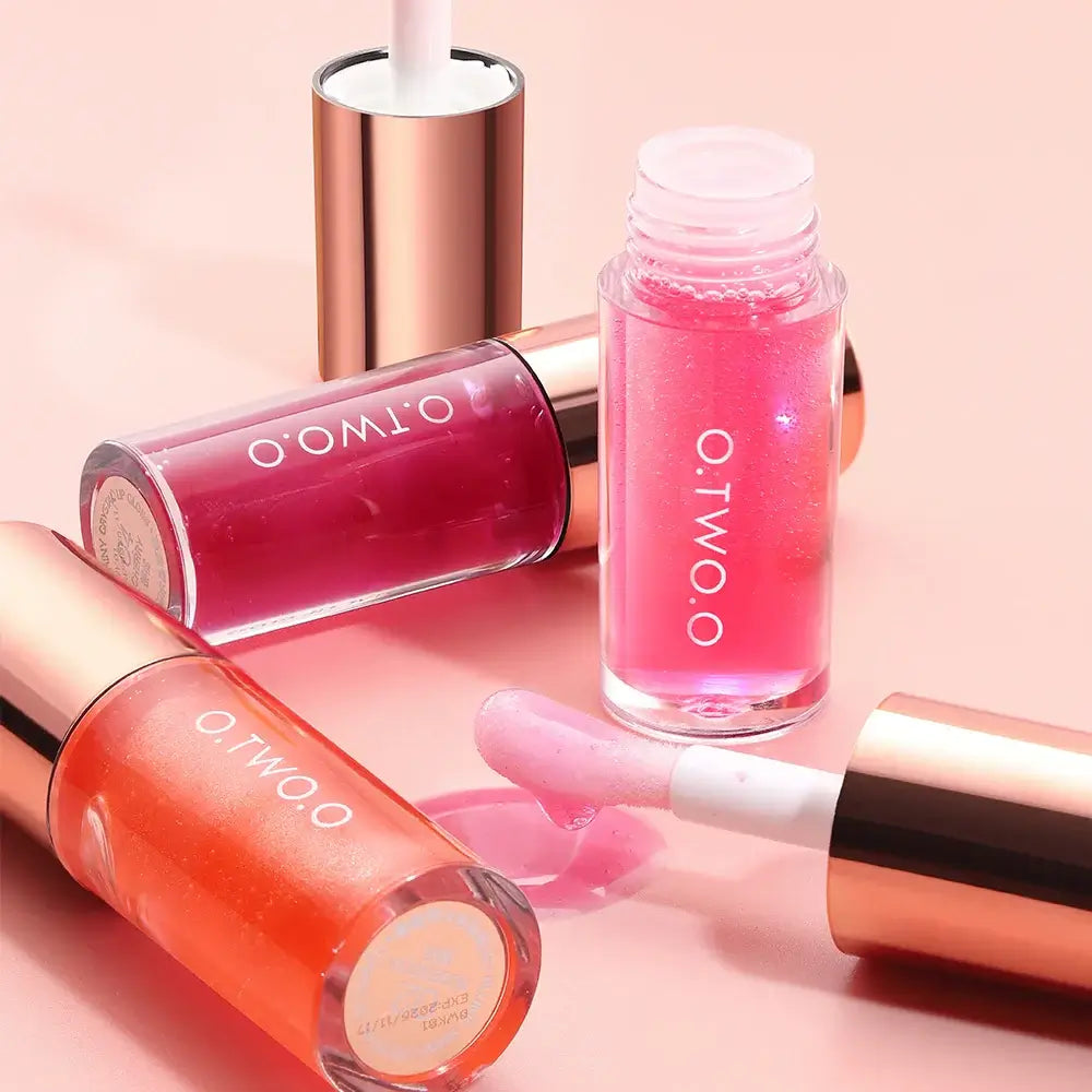 O.TWO.O Lip Plumper Gloss in pink and orange shades on a pink background with applicator wand.
