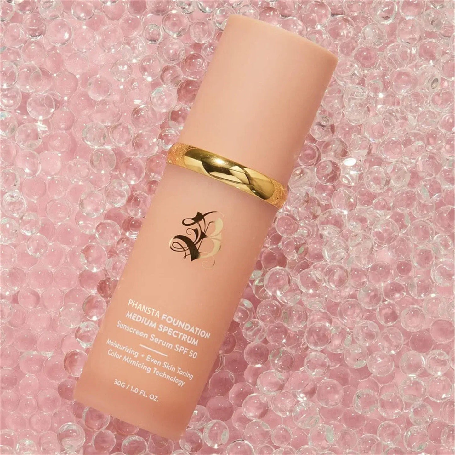 Phansta Foundation Medium Spectrum SPF 50, moisturizing serum with color-matching technology, displayed on pink gel beads.