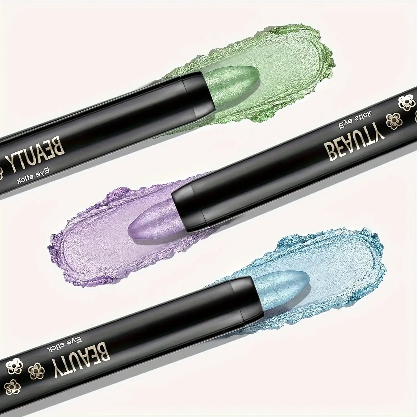 Three colorful eye shadow sticks in green, purple, and blue with vibrant cream swatches.