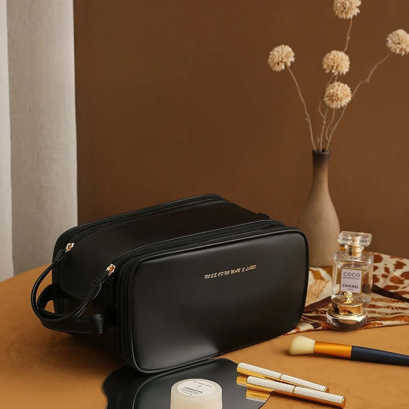 Stylish black double zipper cosmetic bag on a table with beauty products and decorative elements.