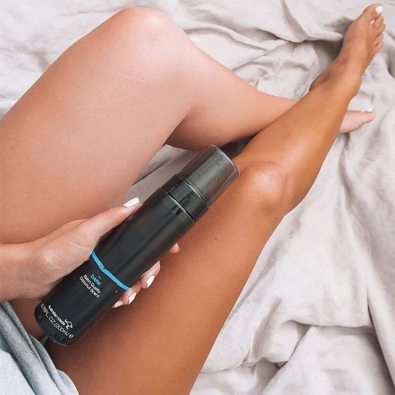 Nutritional moisturizing body cream for universal skin, held by a person with tanned legs on a bed.