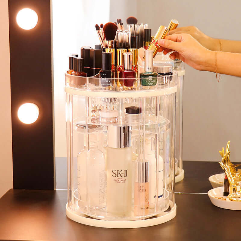 Rotating transparent cosmetics storage rack organizing makeup and brushes on a vanity with soft lighting.