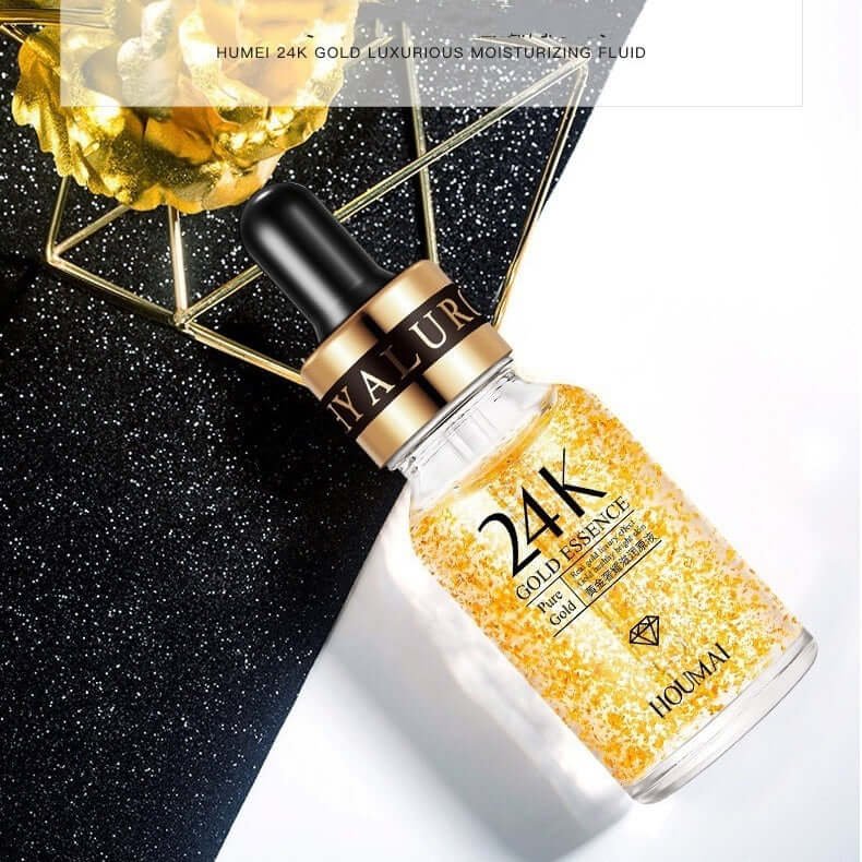 24K Gold Liquid Skin Rejuvenating Essence in a glass bottle with dropper on a reflective surface